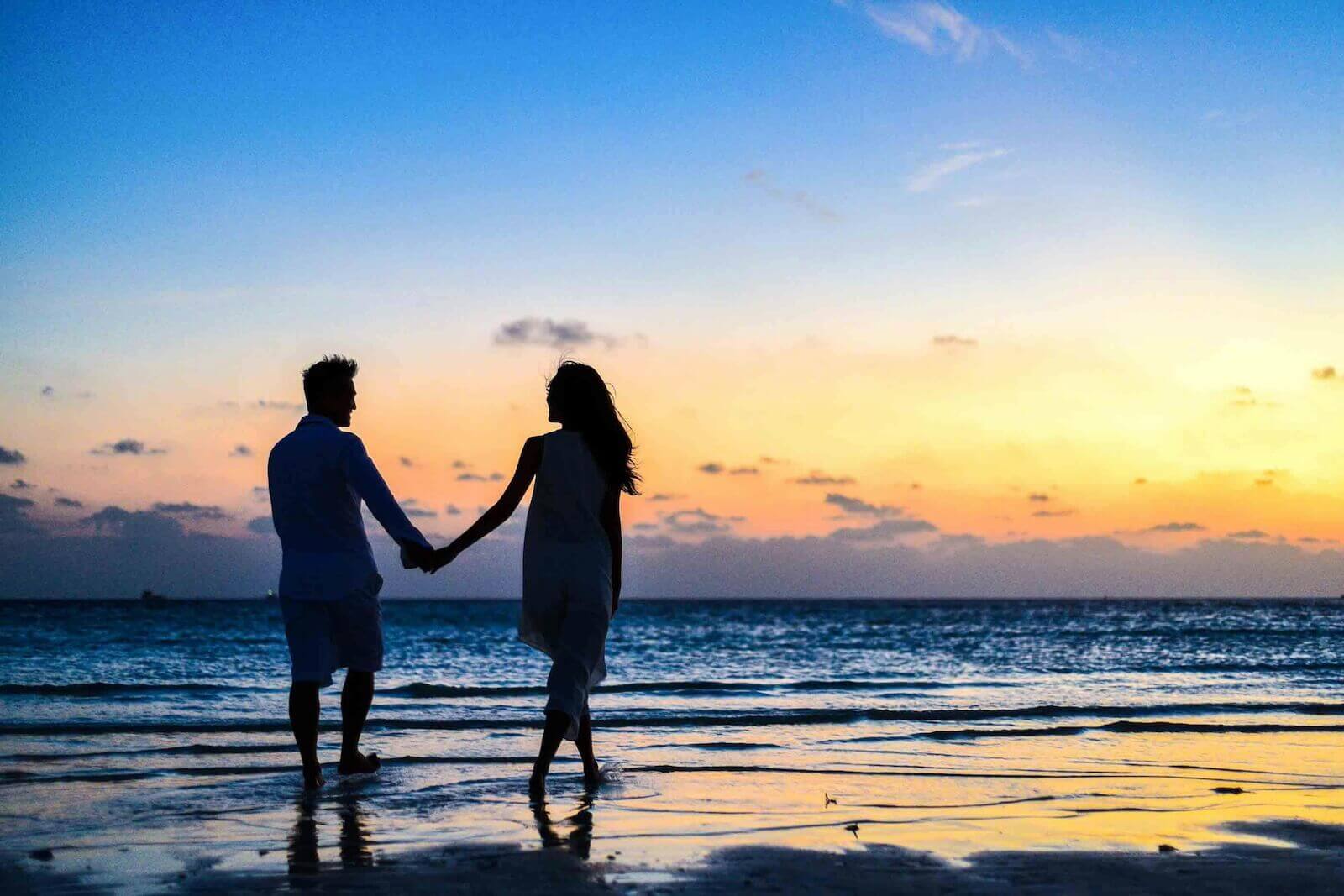 夕映えの中で、リゾートビーチで手をつないで佇むカップル